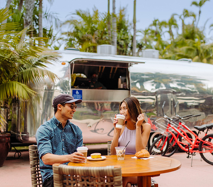 A couple enjoying coffee and pastries at the Airstream Café Grab 'N Go steps away from Bahia Beach and Boat Club.